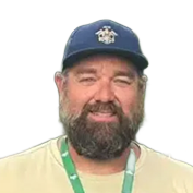 Smiling bearded man in a navy cap and pale yellow shirt with a green lanyard