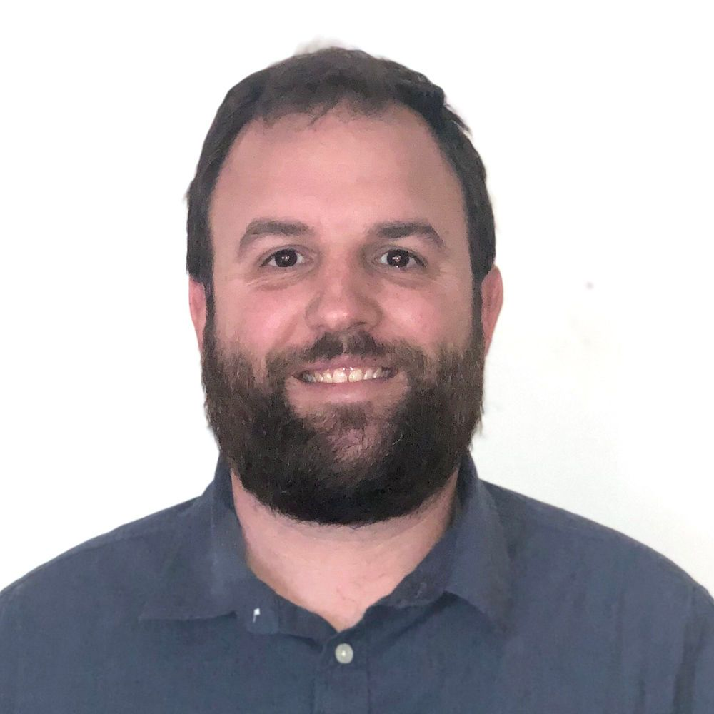 Smiling bearded man in a blue shirt against a white background