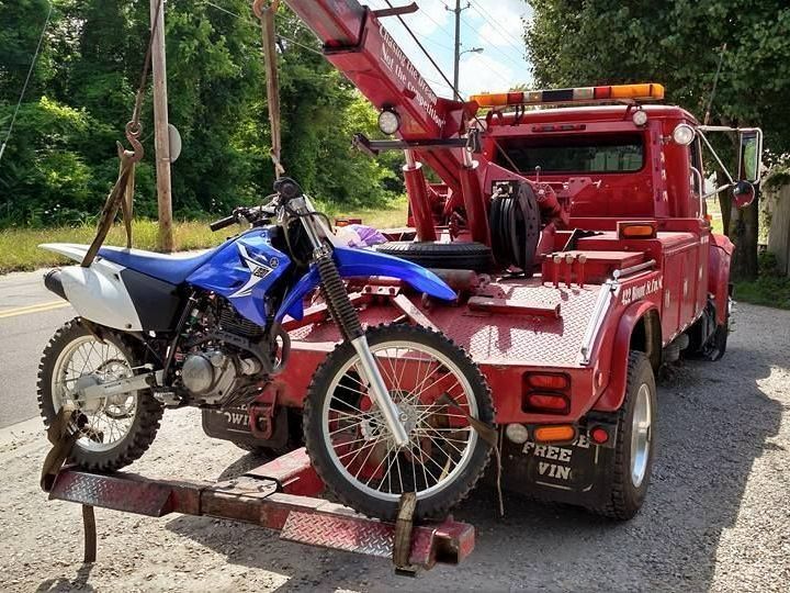 a motorcycle is being towed by a red tow truck