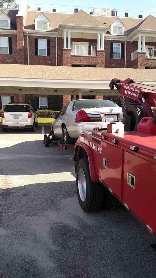 a white car is being towed by a red tow truck
