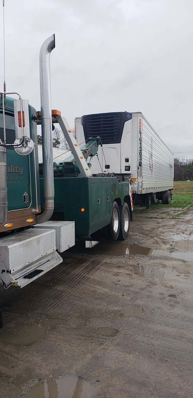 a tow truck is towing a semi truck in a parking lot .