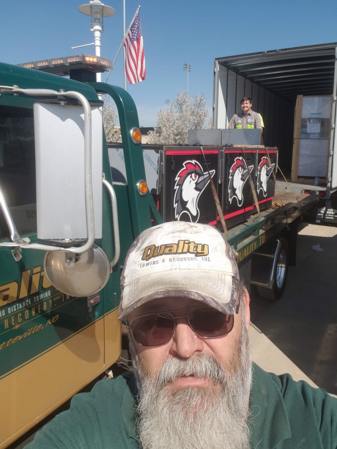 a man with a beard is standing in front of a tow truck .