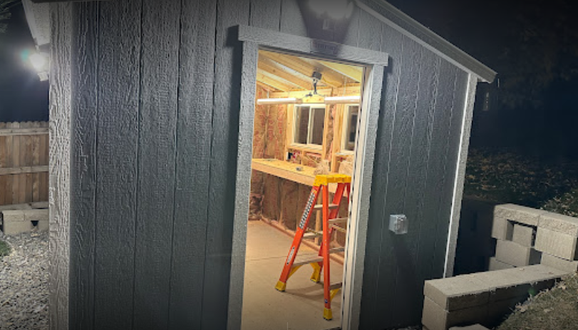 A shed with a ladder in it is lit up at night.