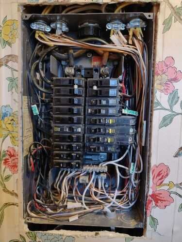 A very old electrical panel with a lot of wires coming out of it.