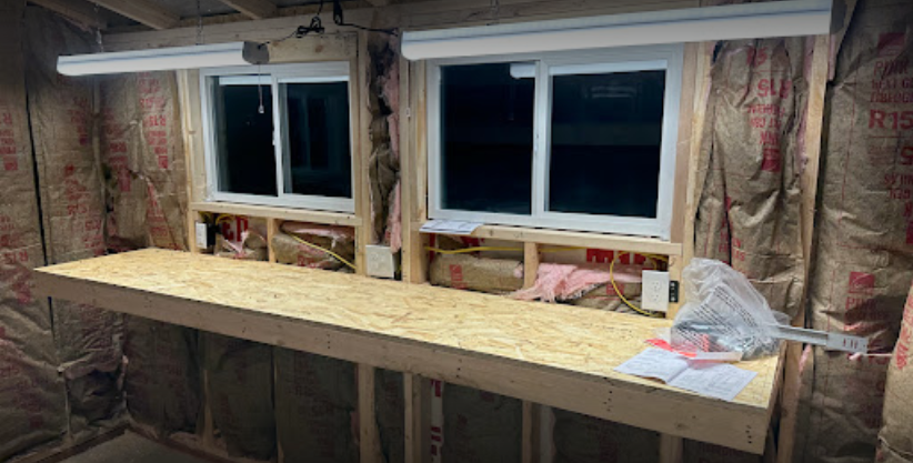 A wooden workbench in a room with two windows.