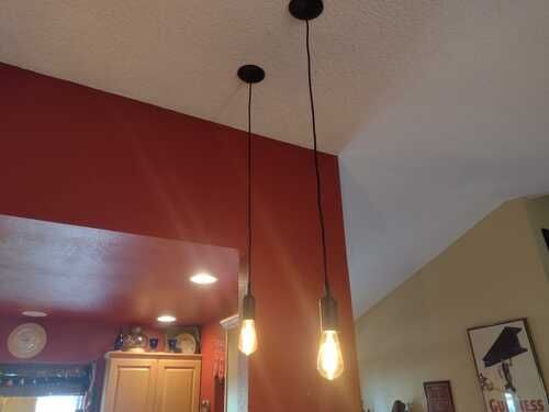 Three light bulbs are hanging from the ceiling in a kitchen.