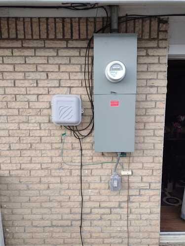 There is a meter on the side of a brick wall.