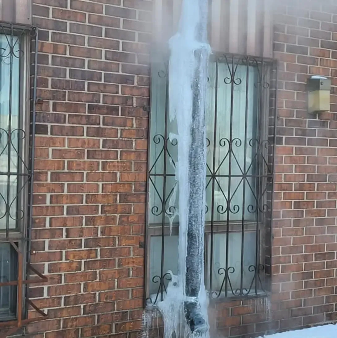 Un bâtiment en briques avec un tuyau d'évacuation recouvert de glace