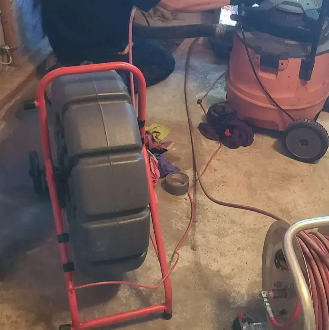 Un aspirateur est posé sur le sol à côté d'un déboucheur de canalisations