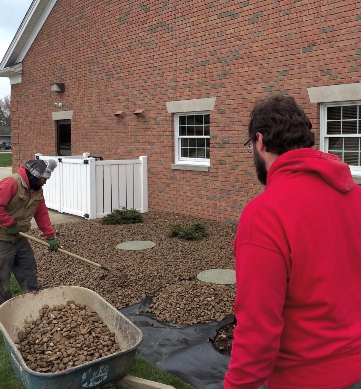 Bako Landscaping person uses a rake to spread gravel over landscape fabric 