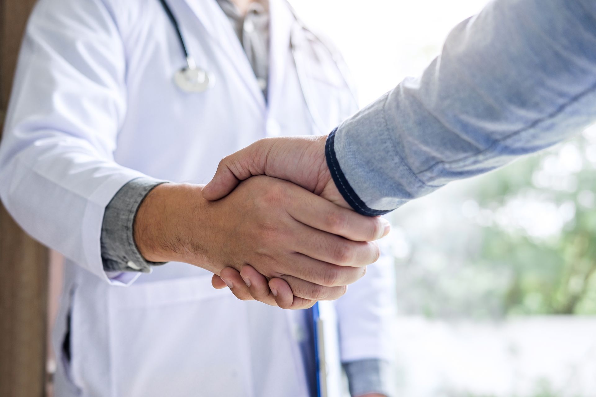 Ein Arzt im weißen Kittel schüttelt einem Patienten die Hand.