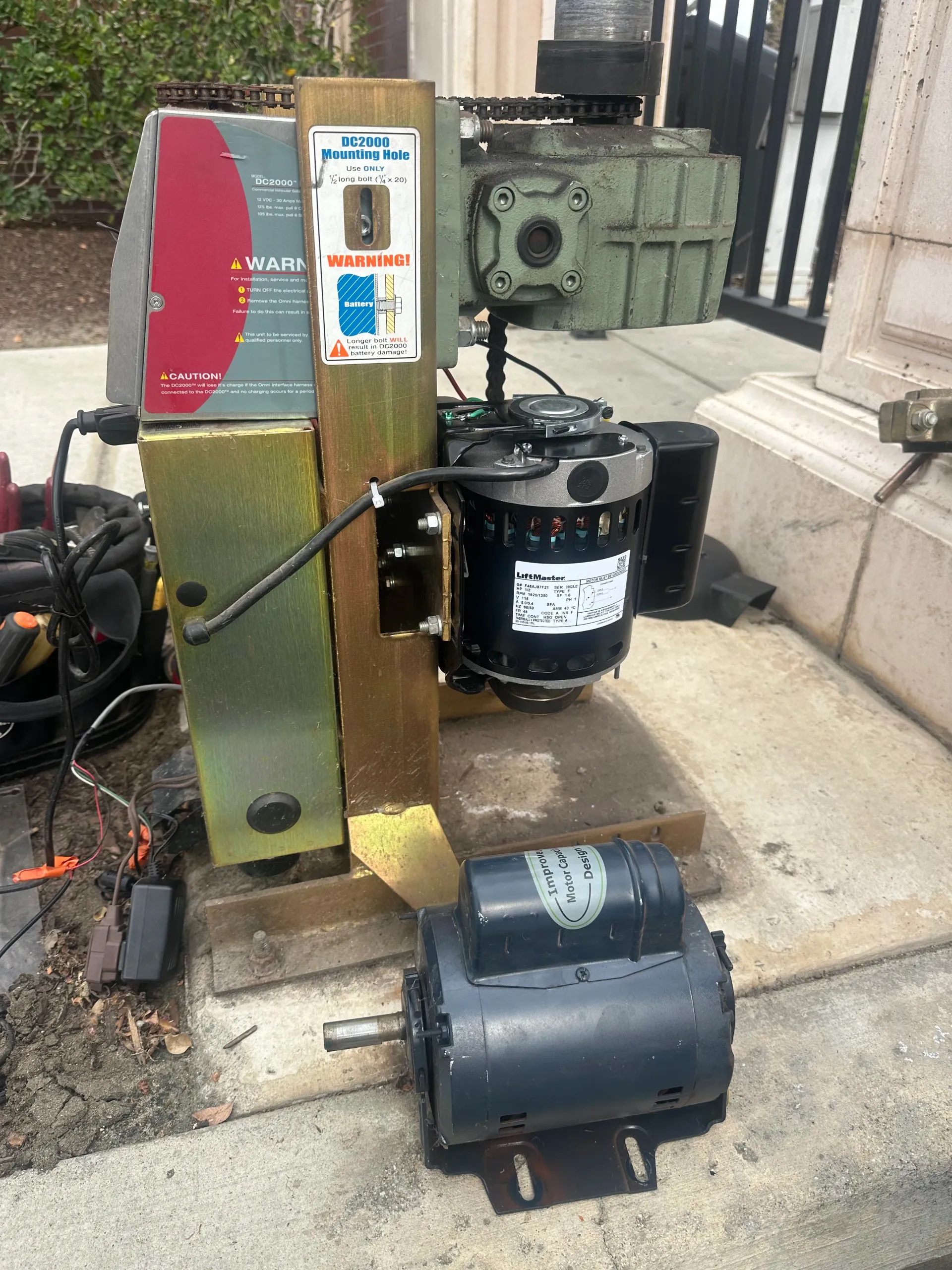Old industrial machine with a red control panel, black motor, and detached motor on a concrete step outdoors in Bakersfield, CA