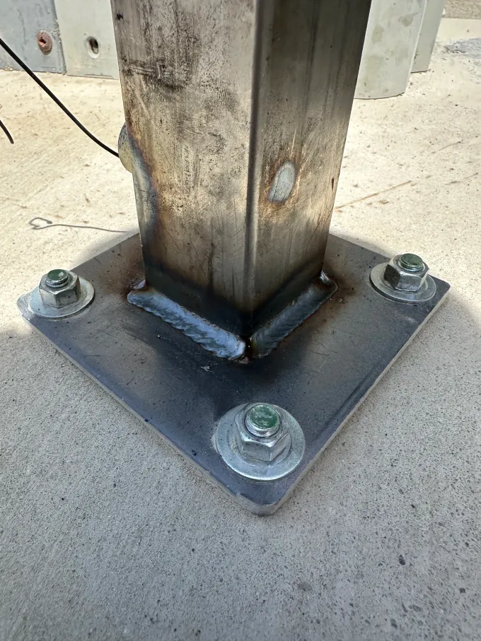 Gate post base plate weld and anchor bolt close up during installation in Bakersfield CA