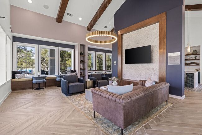Modern living room with vaulted ceiling, large windows, leather sofas, and wall-mounted TV