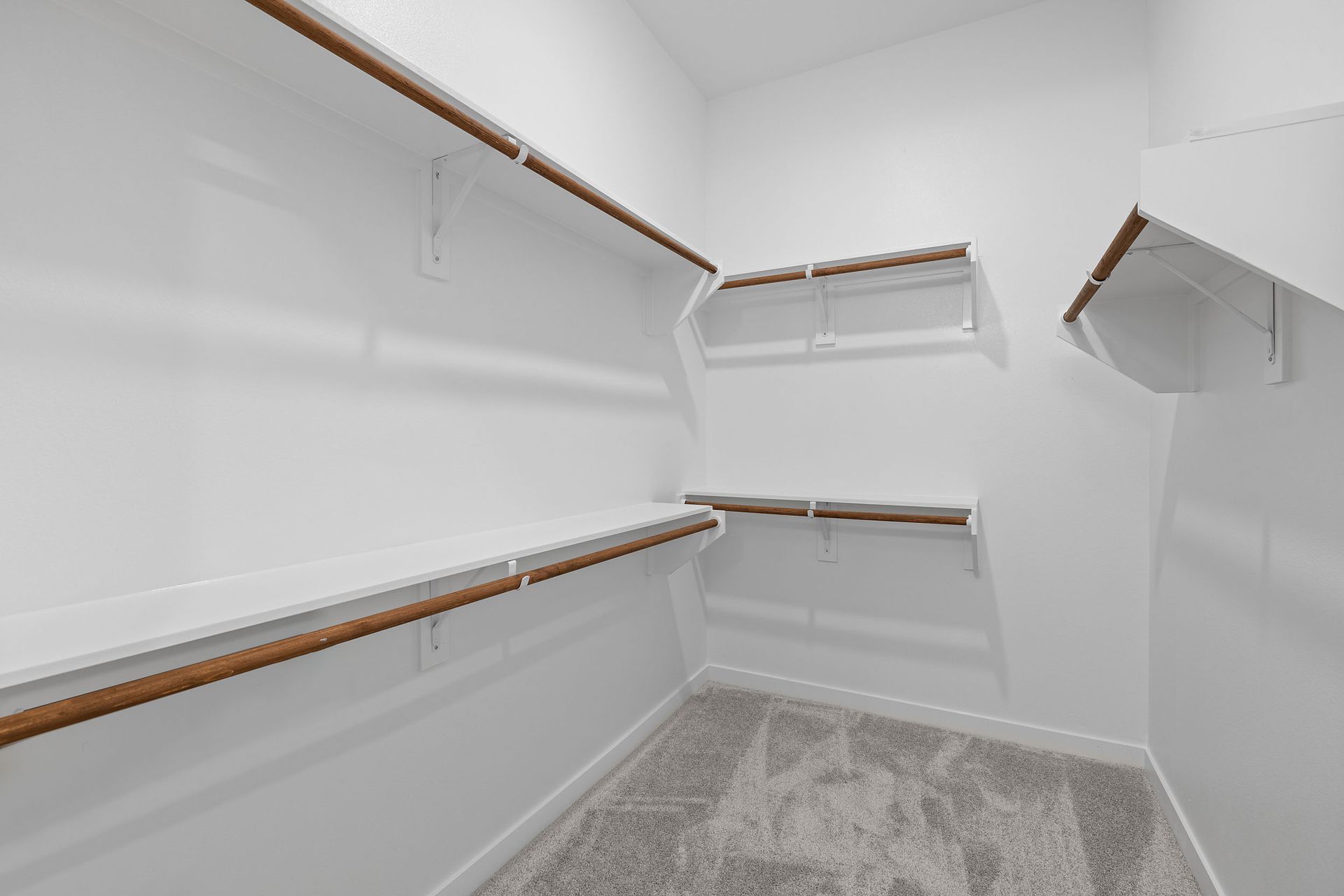 A walk in closet with a lot of shelves and a carpeted floor at The Everett, offering apartments for rent in Northwest Austin, TX