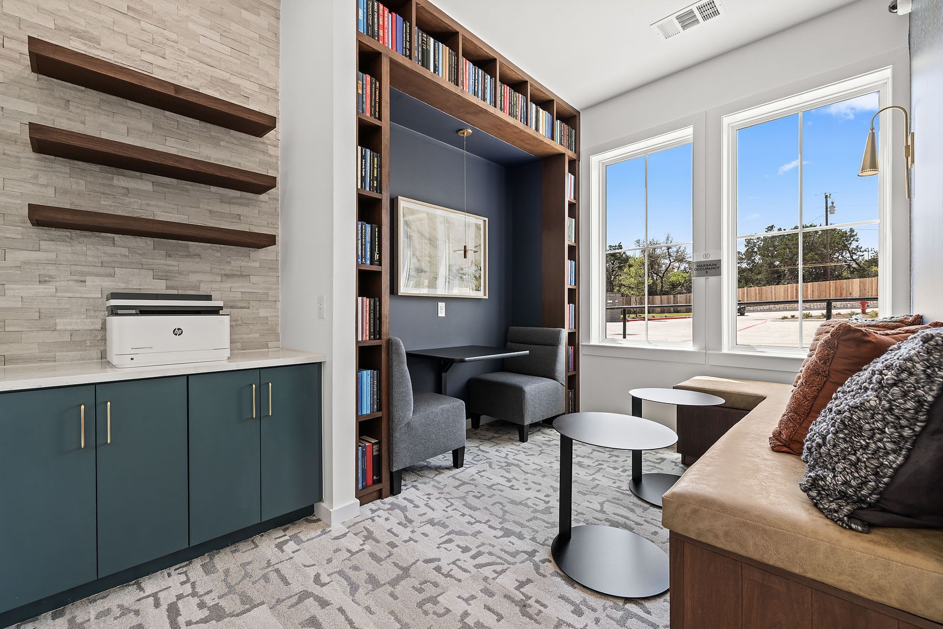 Resident lounge with a couch, chairs, tables, and shelves at The Everett, offering apartments for rent near Lake Travis.