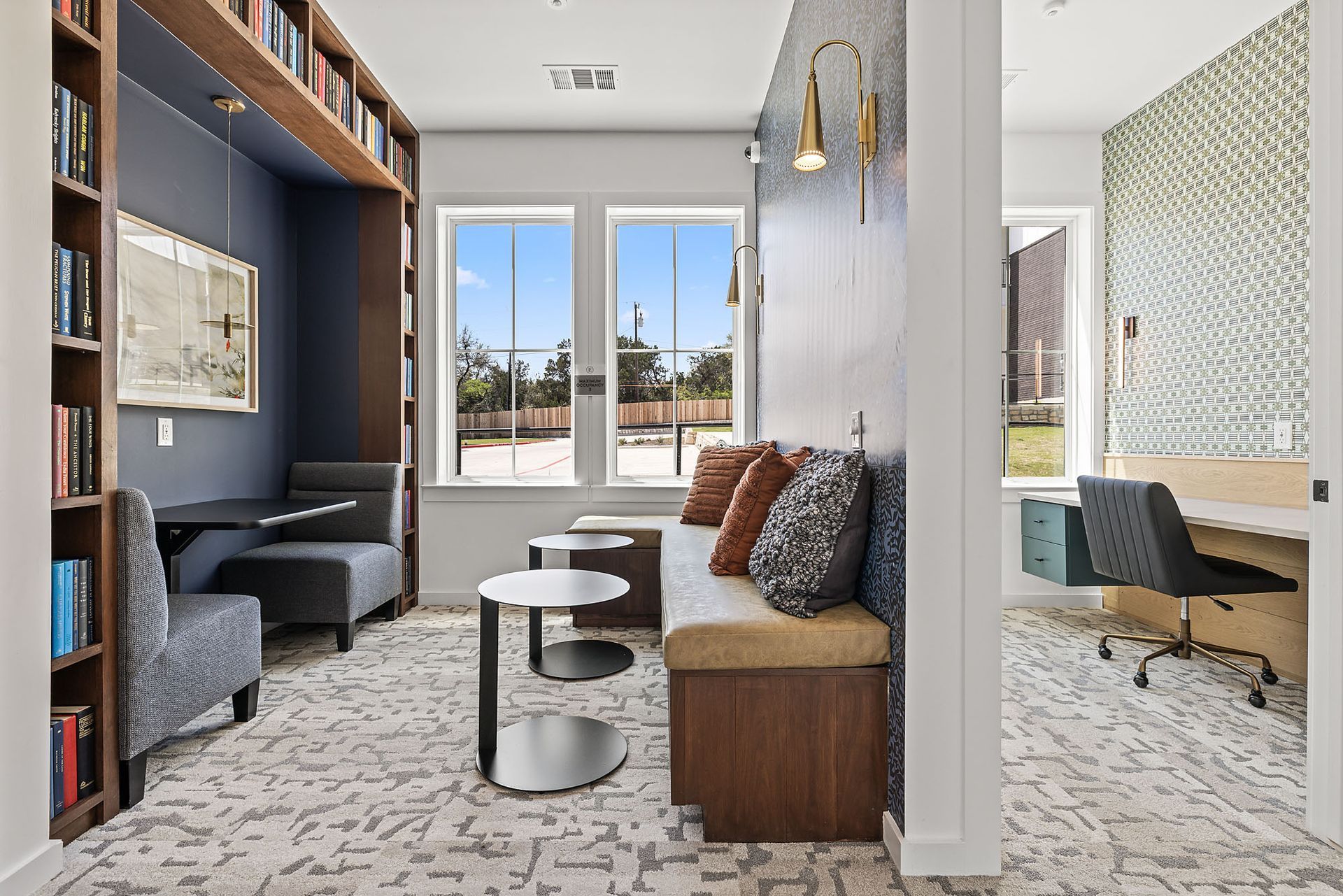 Resident lounge with a couch, chairs, tables, and bookshelves at The Everett, offering North Austin apartments.