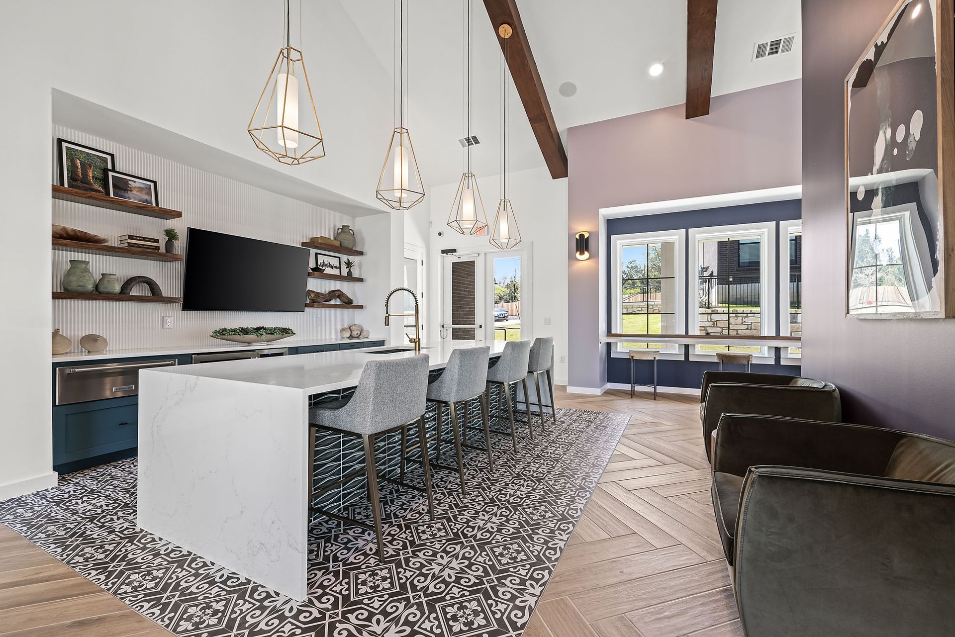 A clubhouse kitchen with a large island and a flat screen tv at The Everett, offering pet-friendly Northwest Austin apartments for rent.