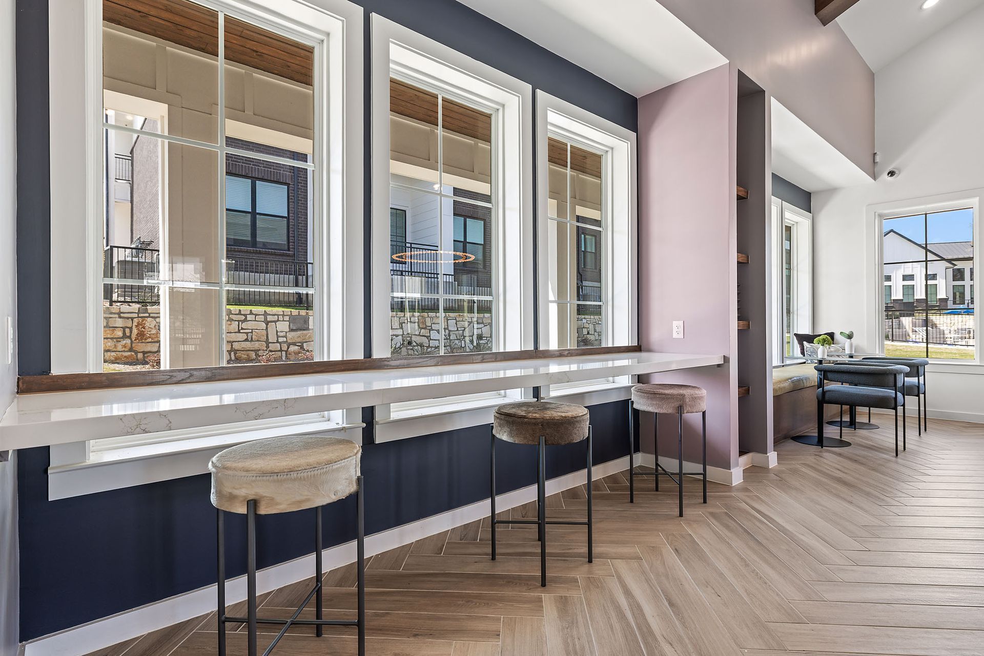 Resident lounge with a long table and stools and a lot of windows at The Everett, offering apartments near H-E-B Grocery Center.