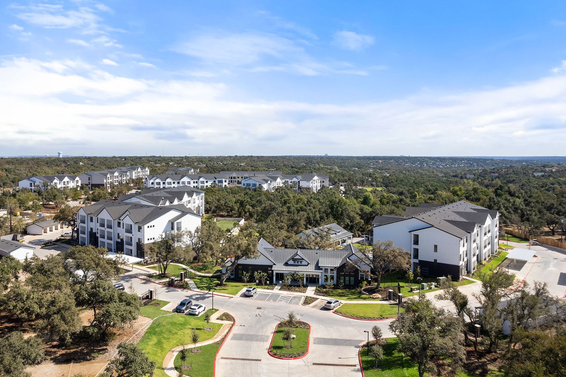 An aerial view of The Everett showcases a residential area with numerous apartment buildings and abundant trees, offering apartments for rent in Northwest Austin, TX.