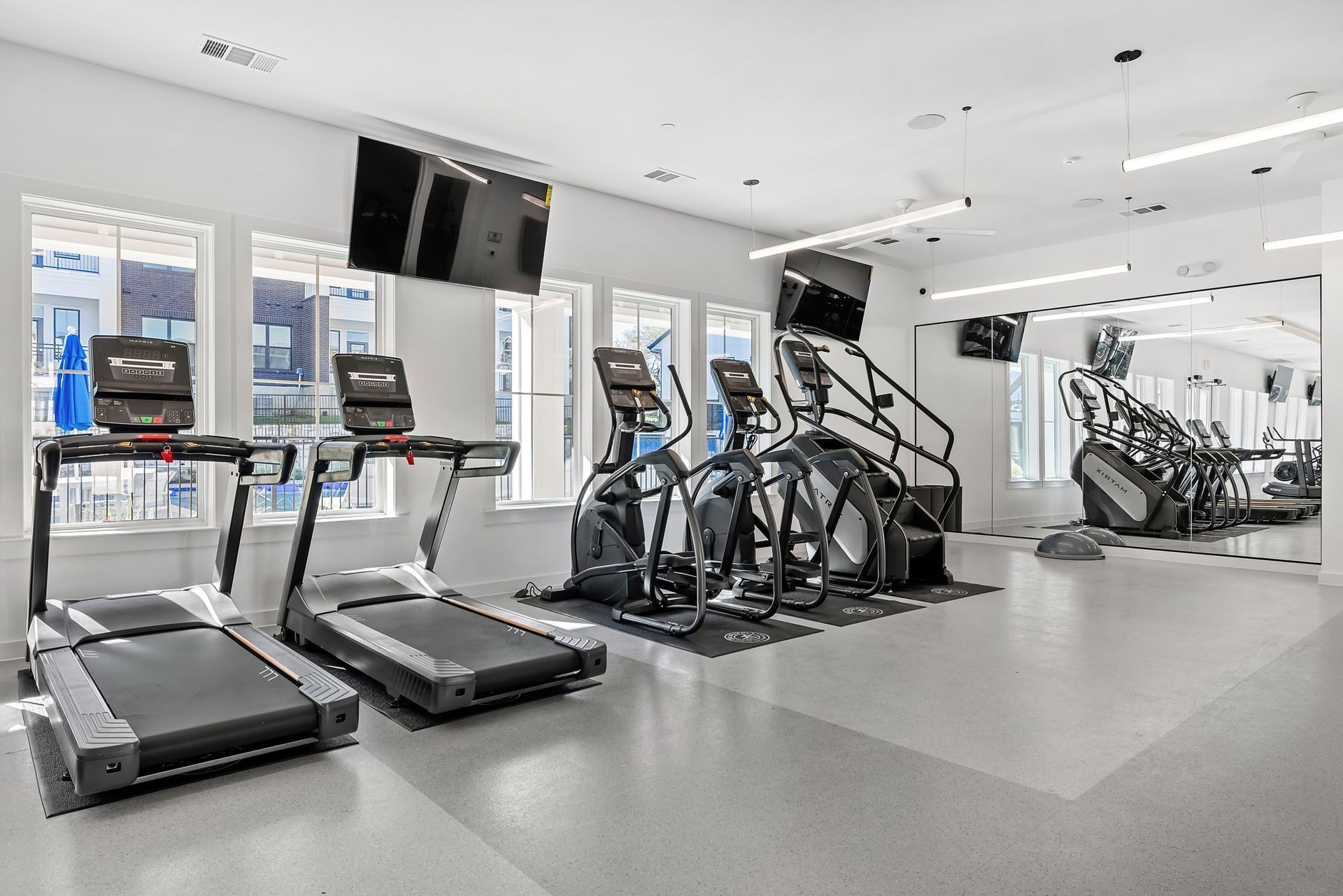 A gym filled with treadmills, exercise bikes, and a television at The Everett. offering apartments in Northwest Austin, TX.