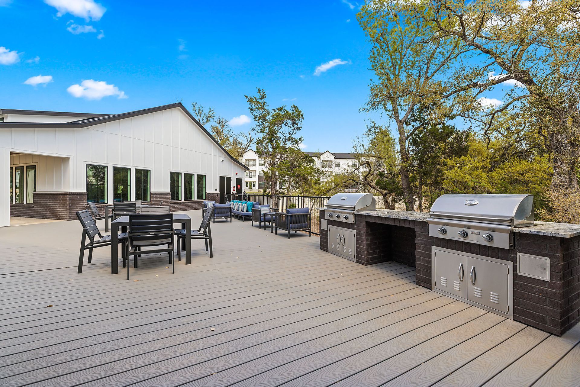 A large deck with tables and chairs and a grill at The Everett, offering apartments for rent in Northwest Austin, TX.