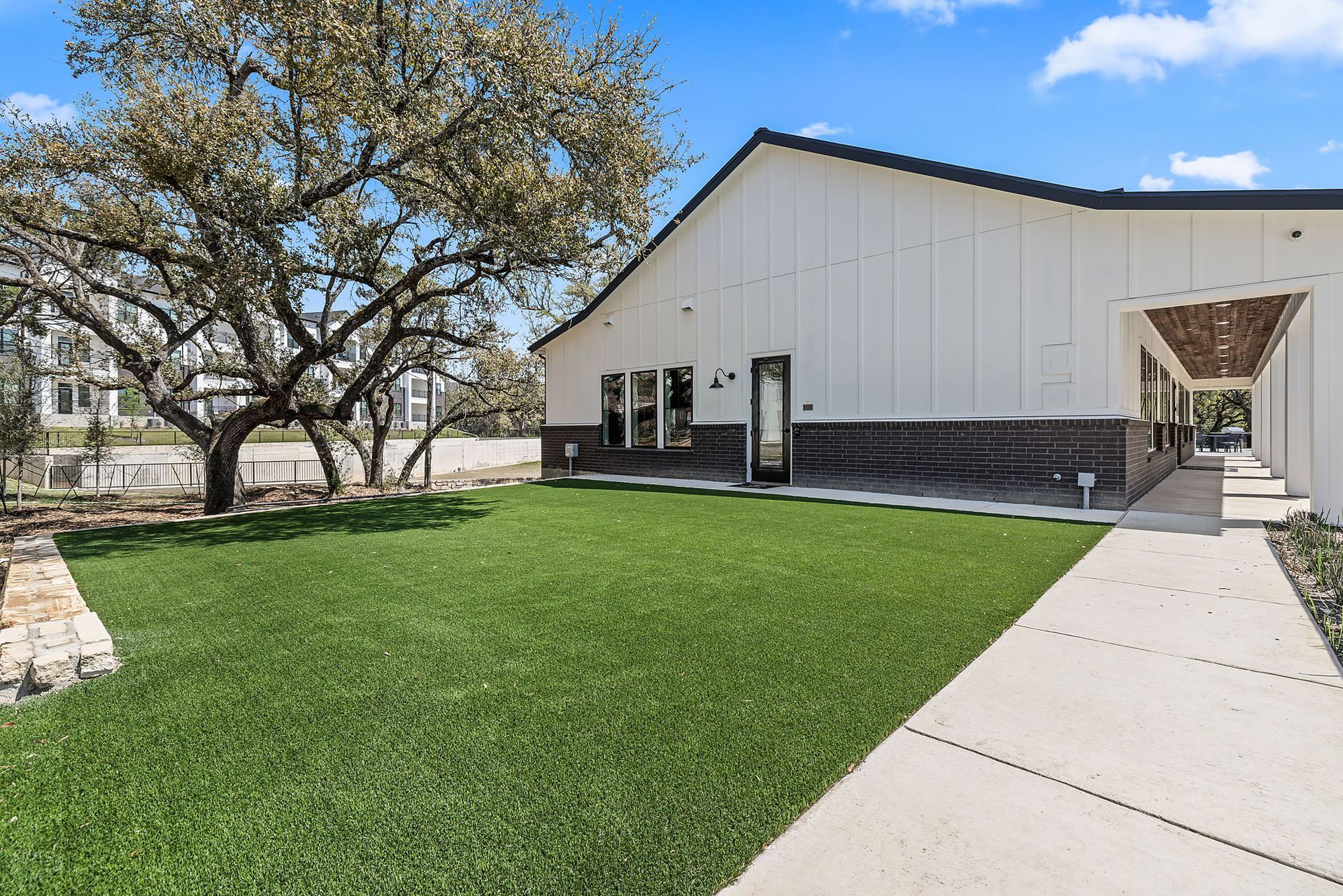 A large white building with a large outdoor yoga lawn in front of it at The Everett, offering apartments in Northwest Austin, TX.