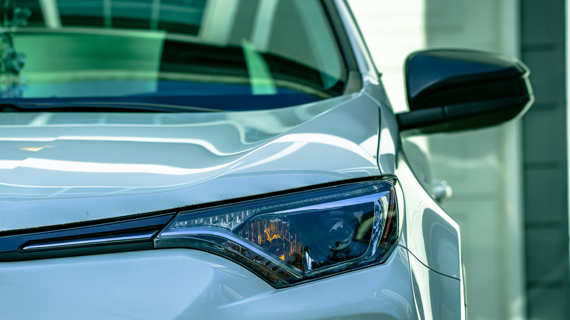 A close up of a white car parked in front of a building.