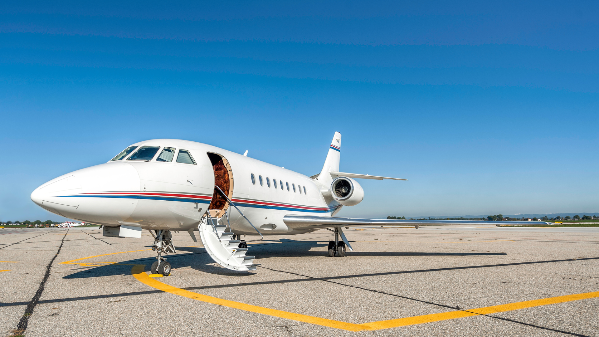 A small private jet is parked on the runway at an airport.