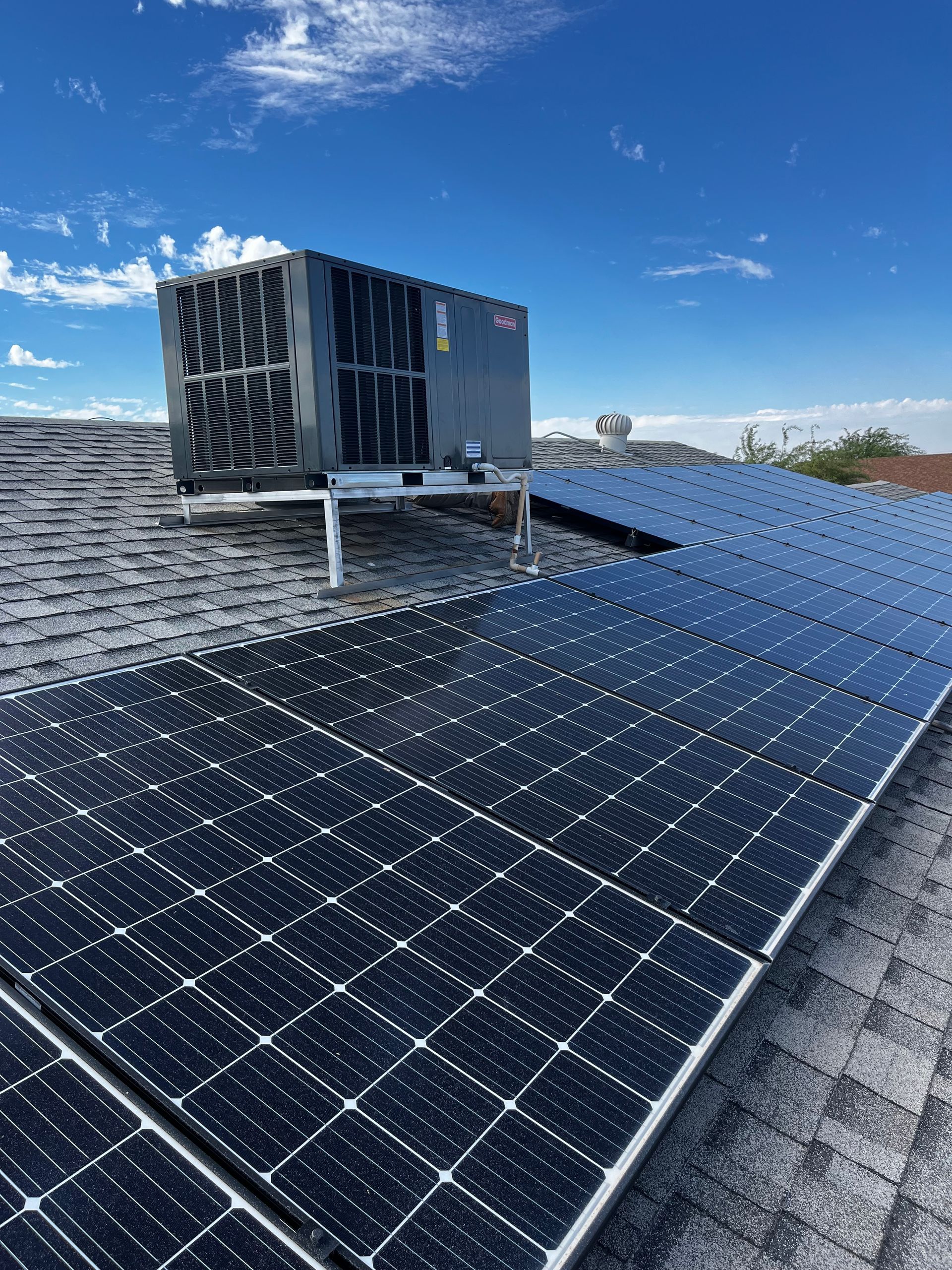 Solar panels and HVAC unit on a rooftop against a blue sky.