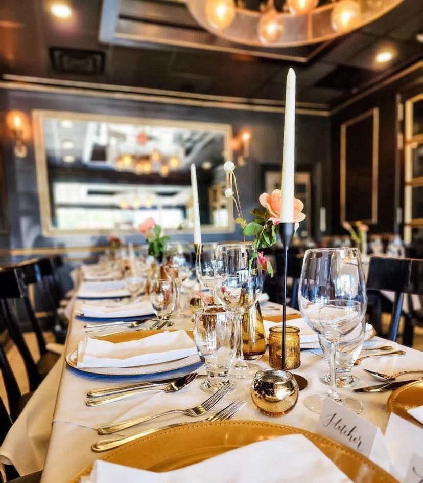 A long table is set for a wedding reception with plates and candles