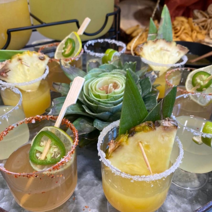 A tray of drinks with pineapples and jalapenos on them