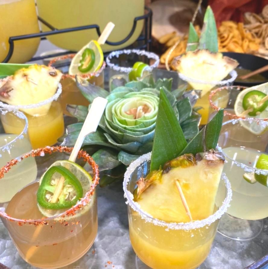 A tray of drinks with pineapple slices and jalapenos