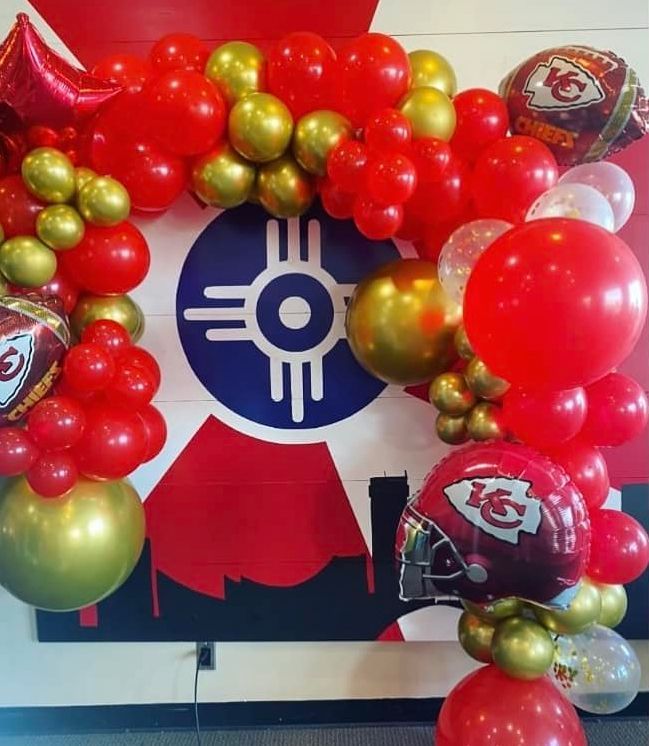 A bunch of red and gold balloons in front of a kansas city chiefs logo