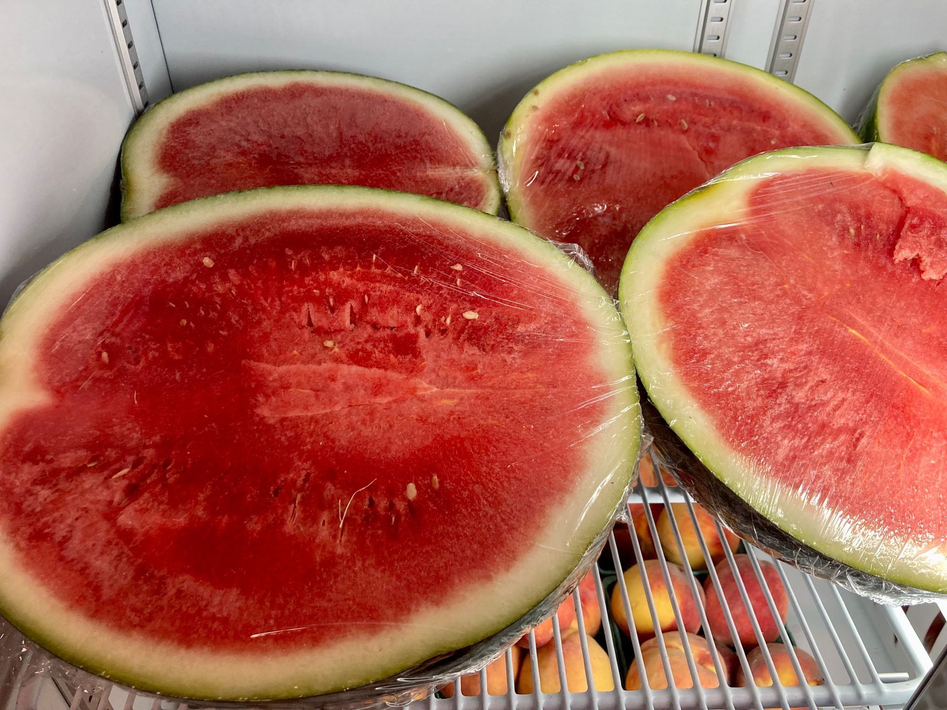Halved watermelons on refrigerator shelves, showing bright red flesh and green rinds. Grasshopper Farms Knightdale, NC