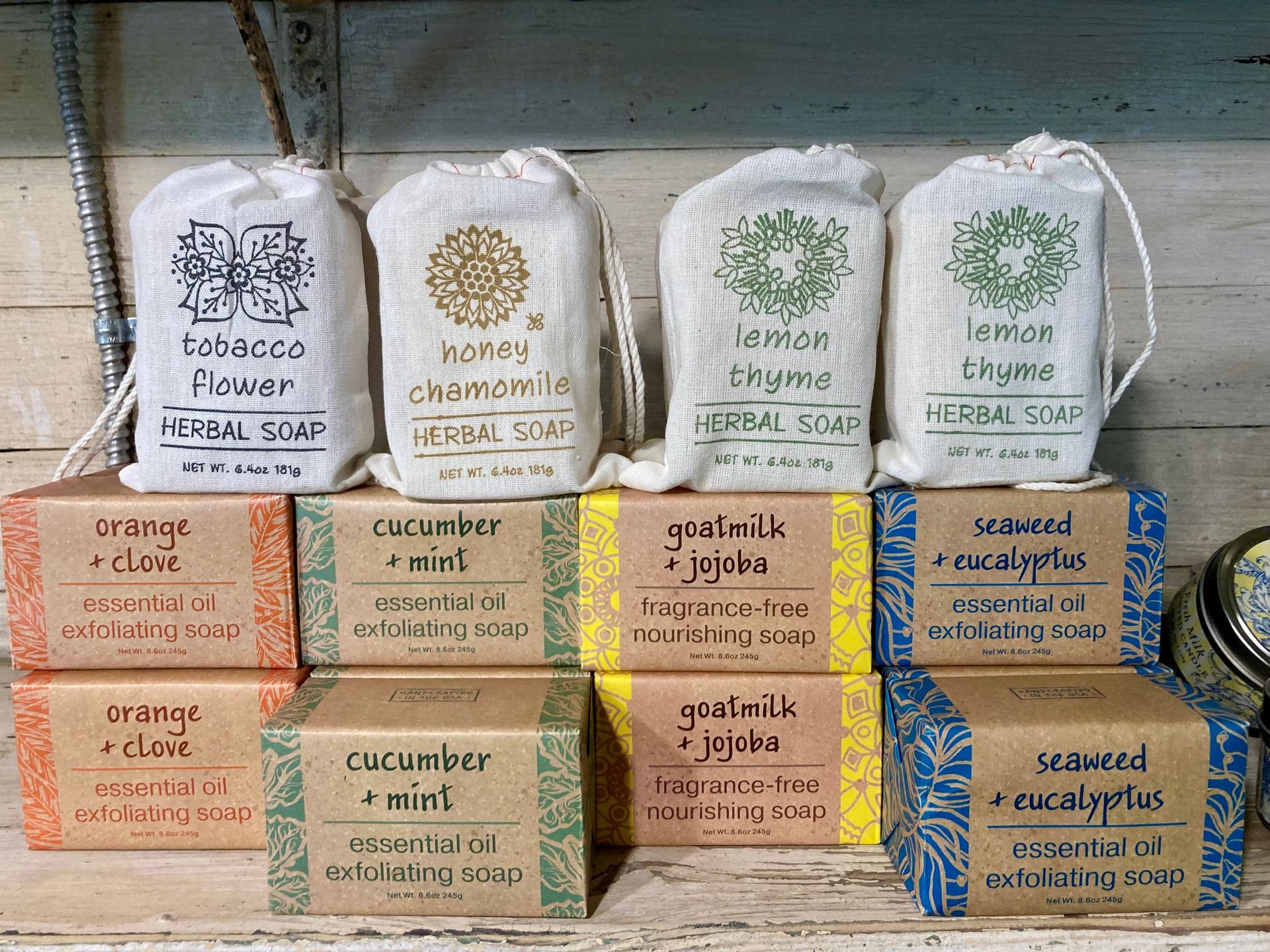 Assorted labeled bags and boxes of herbal teas, stacked in rows on a wooden surface. Grasshopper Farms Knightdale, NC