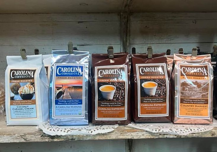 Row of assorted Carolina coffee bags on a store shelf, mostly blue, brown, & orange packaging Grasshopper Farms Knightdale NC