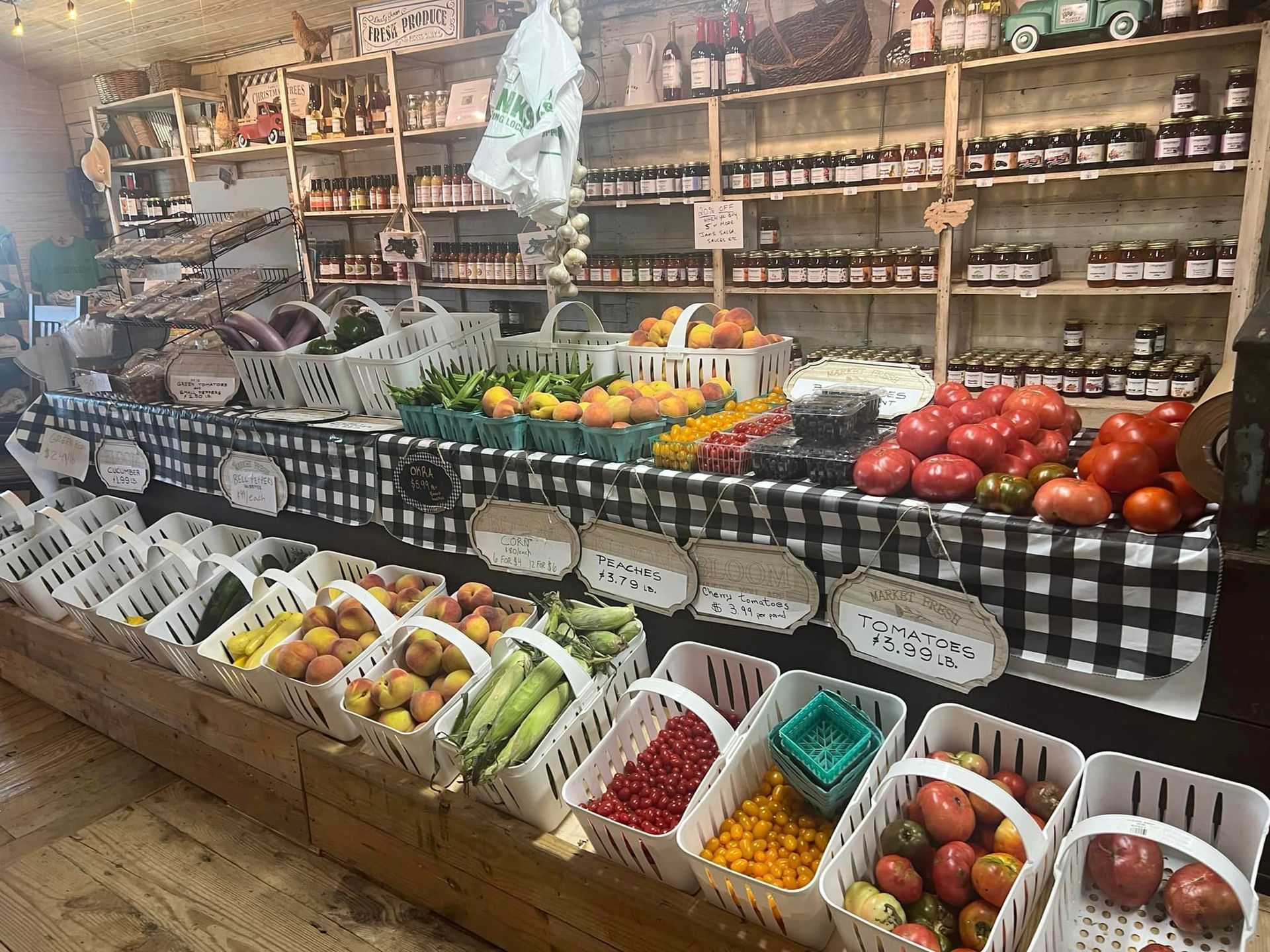 Market stall with colorful fruit and vegetables displayed in baskets & crates along shelves. Grasshopper Farms Knightdale, NC