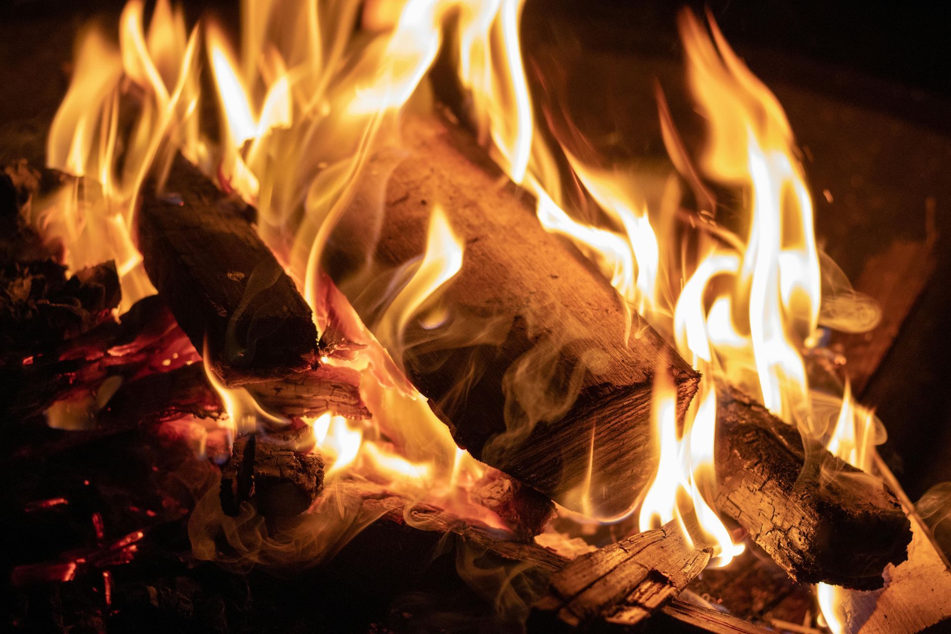 Close-up of burning logs with bright orange flames and glowing embers. Grasshopper Farms Knightdale, NC
