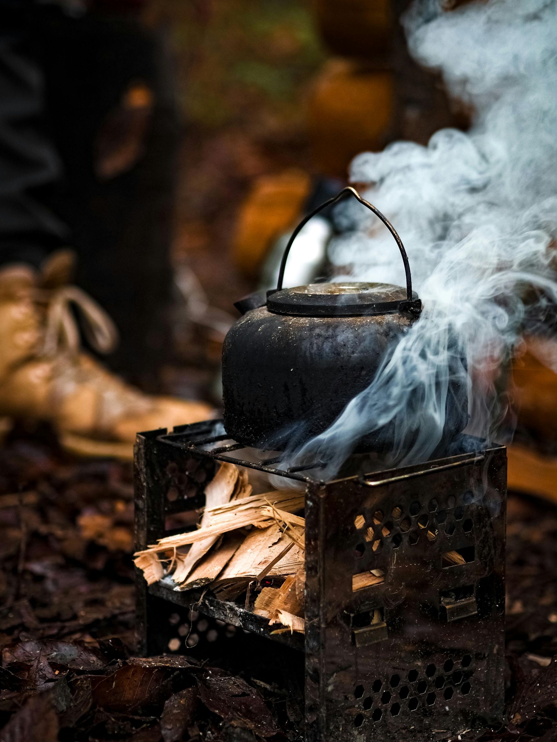 Kettle on a metal smoker with burning wood, sending smoke upward outdoors. Grasshopper Farms Knightdale, NC