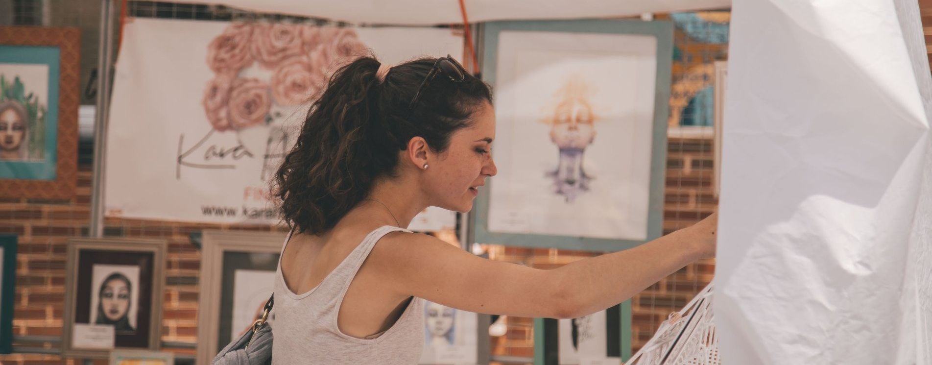 Woman painting on a large white canvas in an art studio with framed artwork on the wall. Grasshopper Farms Knightdale, NC