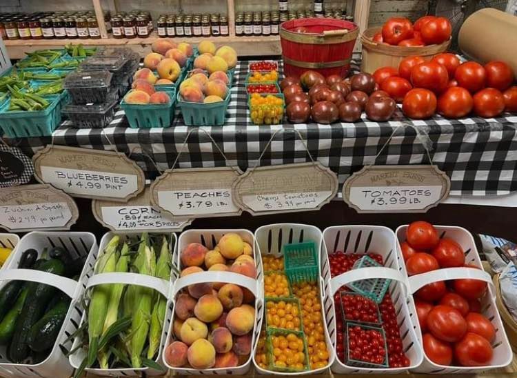Farmers market produce display with peaches, tomatoes, grapes, and other fruits in bins. Grasshopper Farms Knightdale, NC
