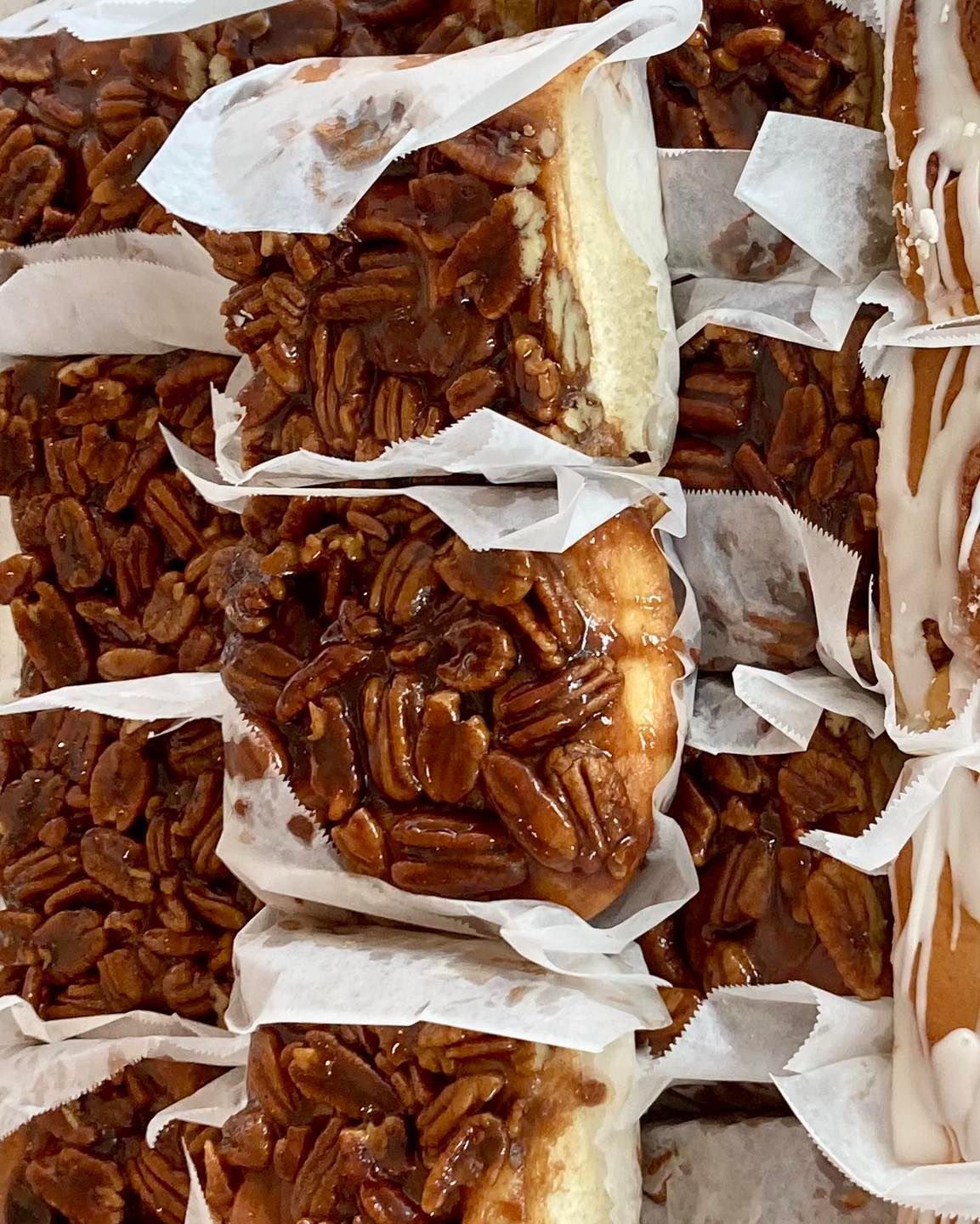 Rows of pecan bars wrapped in parchment, showing glossy caramelized pecans on top. Grasshopper Farms Knightdale, NC