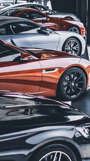 Een rij gestroomlijnde sportwagens in een showroom, waaronder witte, rode en zwarte modellen.