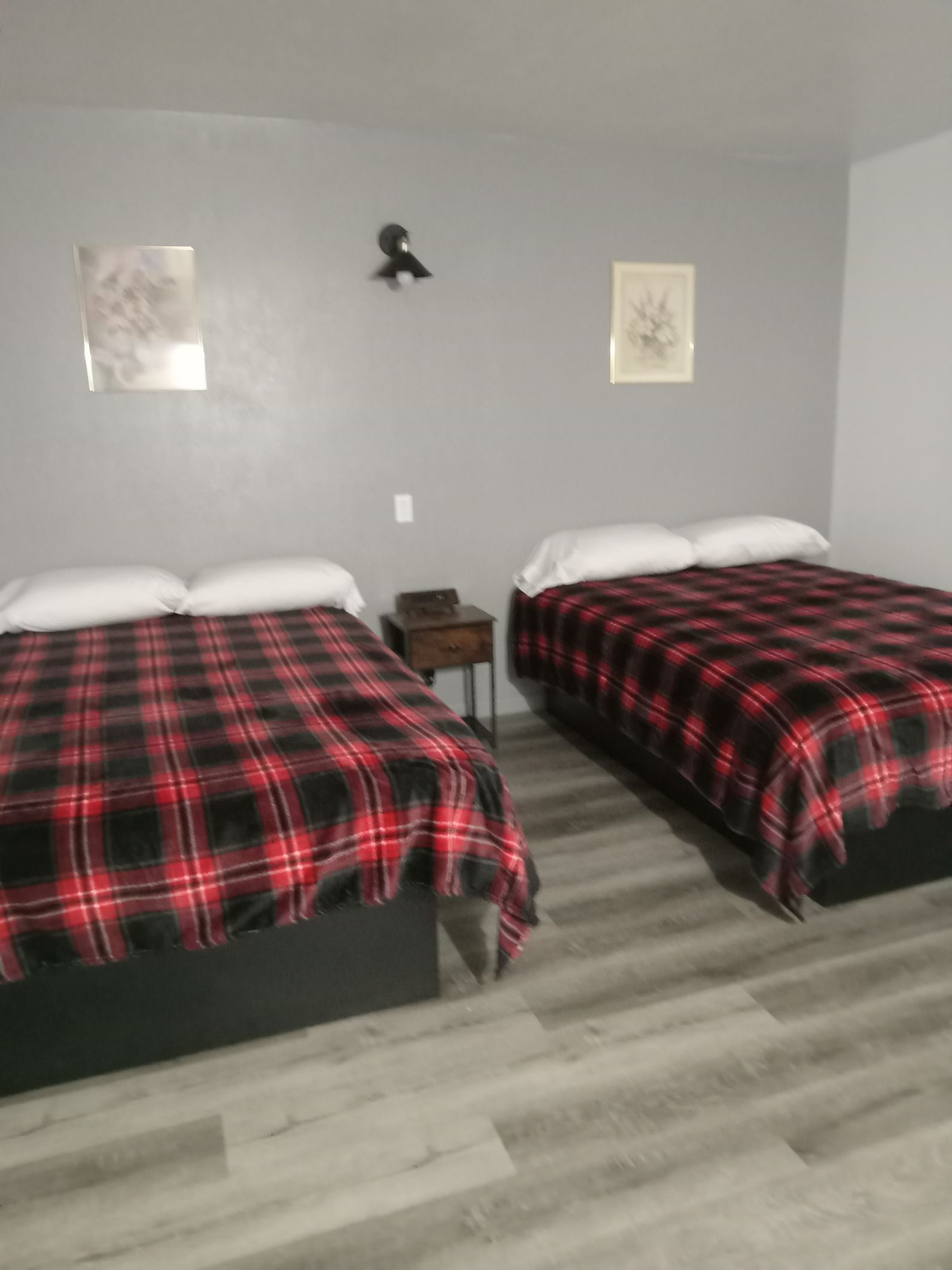 There are two beds in the room with plaid sheets.