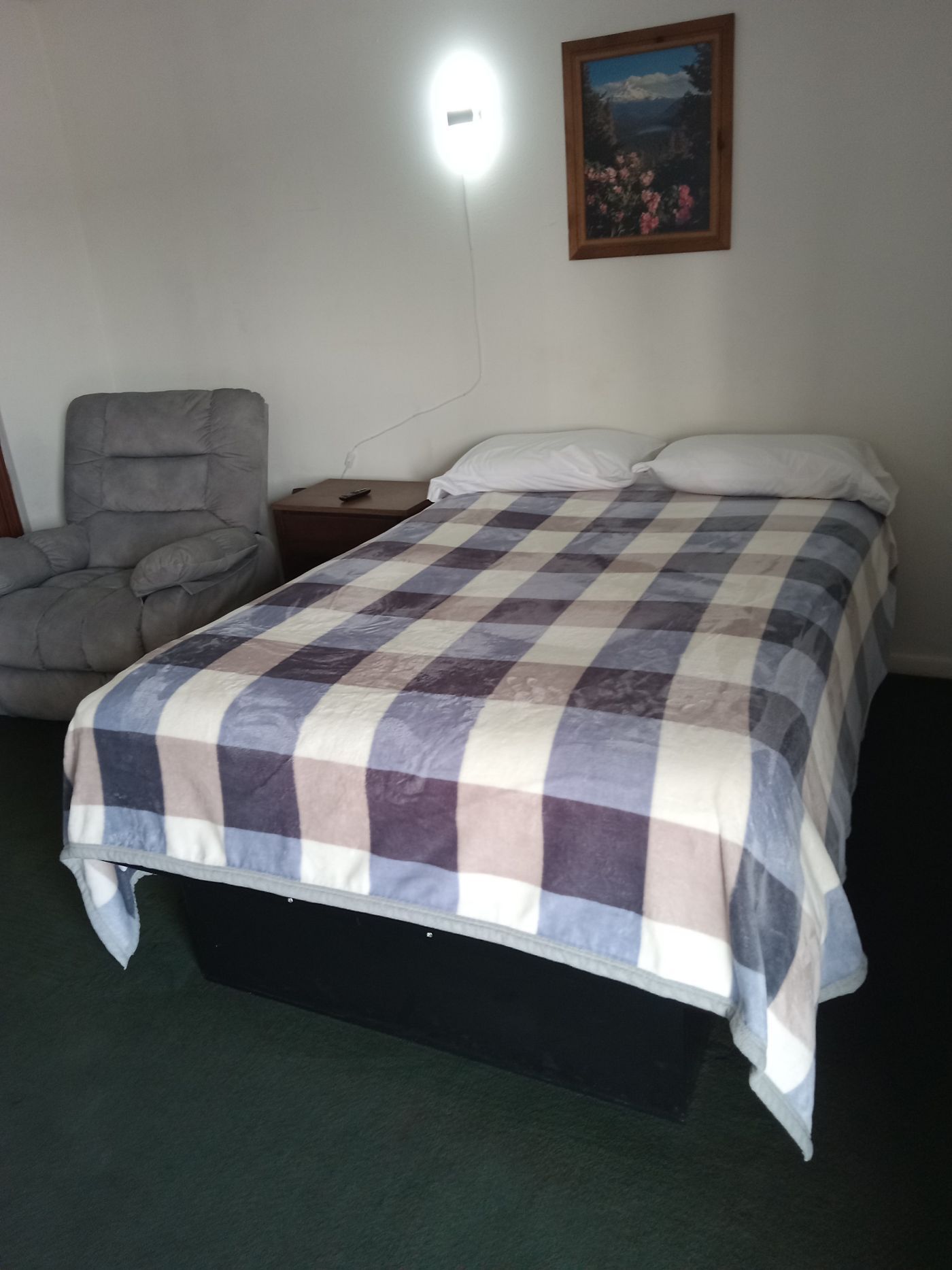 A bed with a plaid blanket in a hotel room