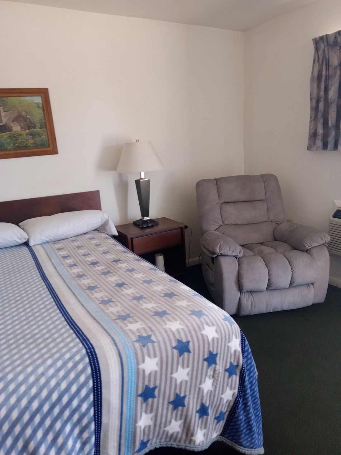 A bedroom with a bed a chair and a lamp