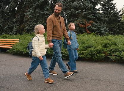 A man and two children are walking down a sidewalk holding hands.