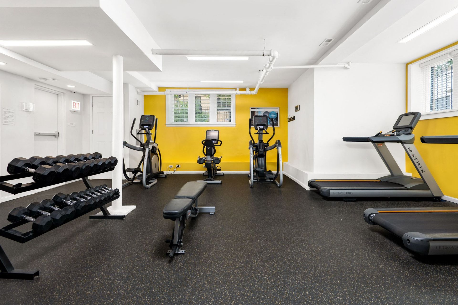 a gym with cardio equipment and weights on the floor