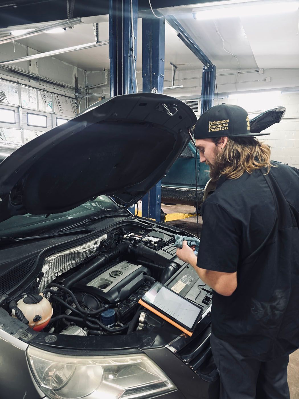 Mechanic inspecting a car engine with the hood open in an auto repair shop